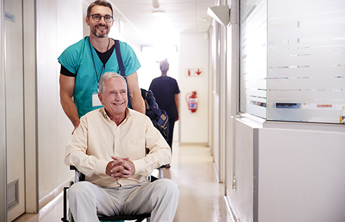 healthcare worker pushing patient in wheelchair